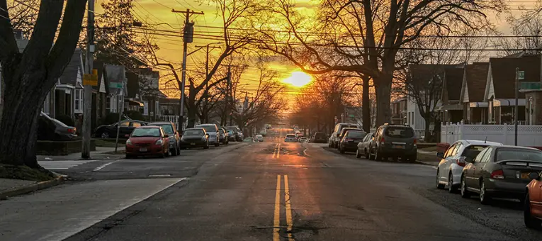 sunset view of typical new york street with houses and vehicles